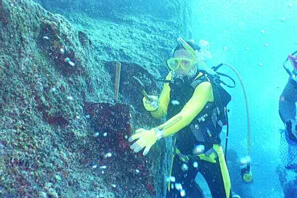 an image of Dr Robert M. Schoch taking samples of encrustations on the Yonaguni No. 1 Monument for analysis