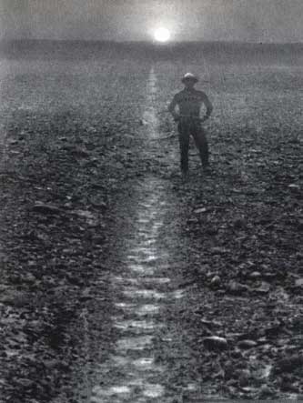 This a photographs of man standing besides one of the straight lines at sunset on the winter  solstice