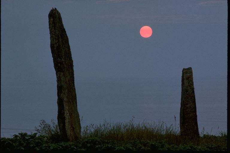 An image of the Stone Row at Ballochroy with the sun setting over the Paps of Jura to the South-East