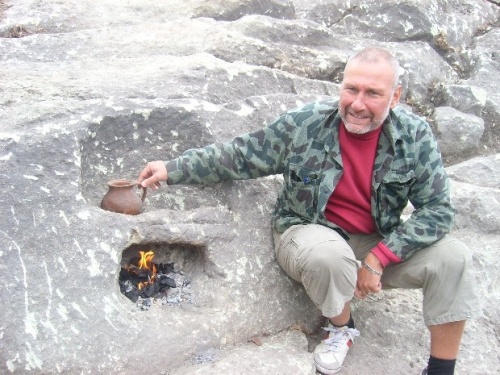 an image taken by Darik News of Bulgarian archaeologist Nikolay Ovcharov demonstrating how the ancient rock stove that he found at Perperikon works, which is also a clickable link directly to the Novinite story